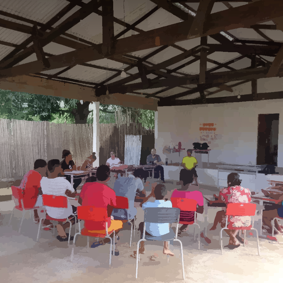 Podemos ver um grupo de pessoas reunidas em um espaço comunitário, para uma reunião.