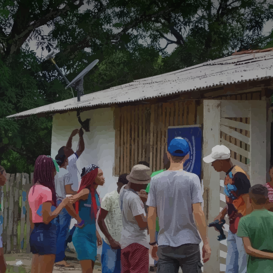 Podemos ver um grupo de pessoas reunidas em um espaço externo, para a implementação de um nodo da rede.